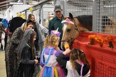 穿着万圣节服装的孩子们在马厩里抚摸马